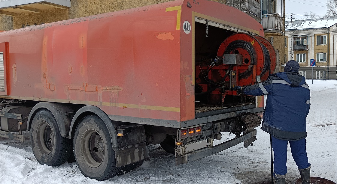 Каналопромывочная машина и работник прочищают засор в канализационной системе в Шимске